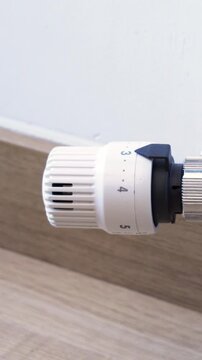 Thermostatic valve being adjusted to a lower setting to reduce heat and save money. Could be reversed to increase the heat. Dolly shot.