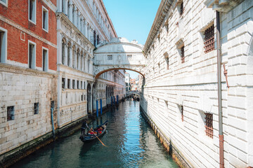 Obraz premium Gondola passing under Bridge of Sighs on canal between historic buildings in Venice, Italy