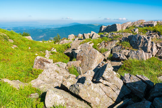 mountain landscape with stones and grass. view of carpthian mountains in summer. white sharp stones on the rolling hills on top of mountain range under blue sky