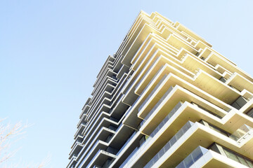 Low-angle view of cascading balcony structure on contemporary residential tower. Illustrates aspirational urban growth, prestige-oriented housing development, and sculptural residential engineering. © tanyatorgonskaya