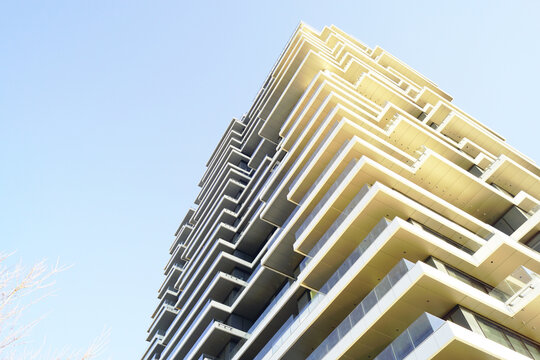 Low-angle view of cascading balcony structure on contemporary residential tower. Illustrates aspirational urban growth, prestige-oriented housing development, and sculptural residential engineering.