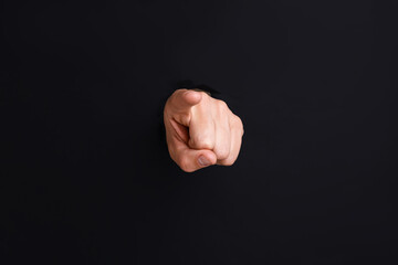 Man pointing at camera through hole in black paper, closeup © New Africa