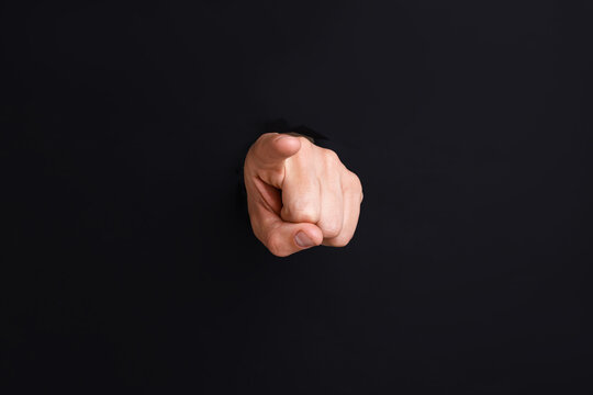 Man pointing at camera through hole in black paper, closeup