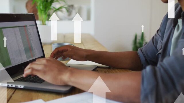 Man typing on laptop at table, generating animated arrows over screen and showing business growth