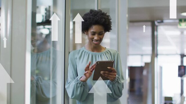 Woman tapping and swiping tablet by glass wall causing rising arrows while inputting business data