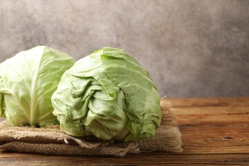 Fototapeta premium Fresh whole cabbages on wooden table, closeup. Space for text