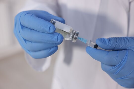 Vaccination. Medical worker filling syringe with medication indoors, closeup