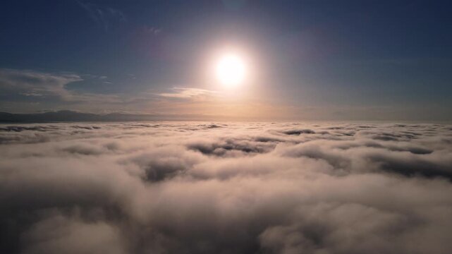 Aerial view of a thick sea of clouds under a bright morning sun with a clear blue sky in Purwokerto, Jawa Tengah, Indonesia.