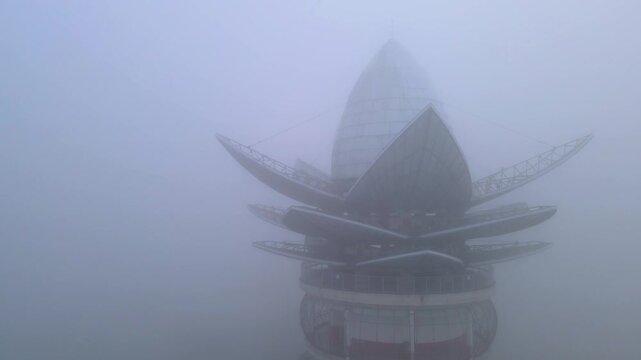 Aerial view of the lotus-shaped Menara Pandang Teratai tower shrouded in dense morning mist and fog Purwokerto, Jawa Tengah, Indonesia.