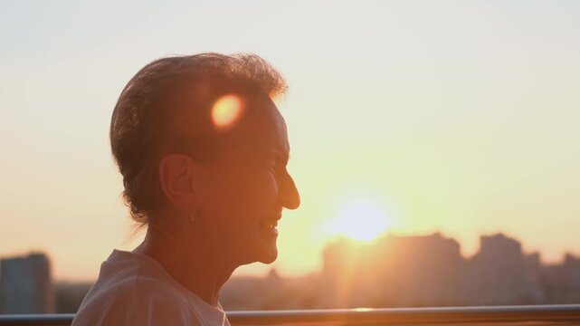 A cheerful smiling old woman is rejoicing at sunset