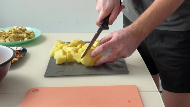 Closeup Chopping Peeled Potatoes Into Uniform Chunks On Small Cuttingboard, Chef Hands Arranging Pieces