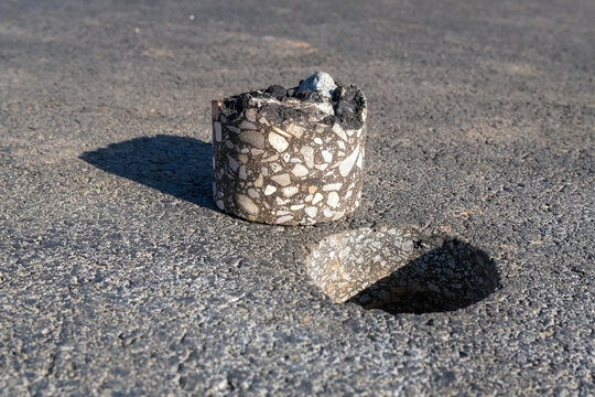 Asphalt Core Sample Lying Near Drilled Hole in Road Surface Pavement Inspection and Quality Testing Concept