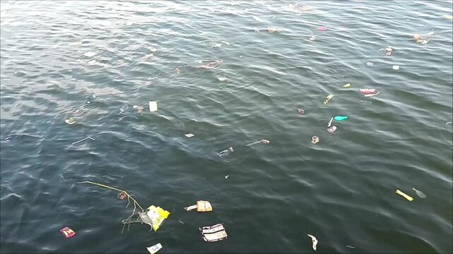 Floating plastic waste and marine debris drifting across polluted water surface, highlighting environmental contamination, ocean pollution, and the global issue of water waste