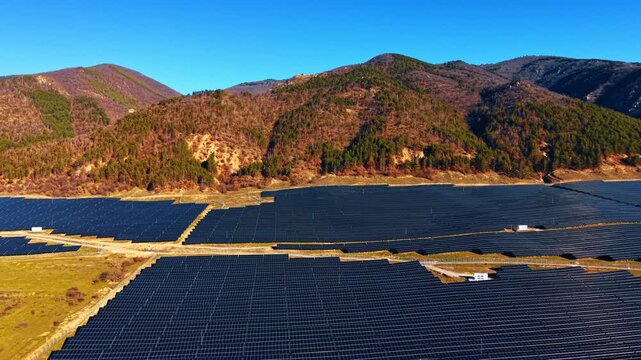 Huge fields of modern solar panels at the mountain foot. Bright sun lights the landscape covered with photovoltaic cells.