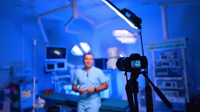 Professional camera arranged for footage in the modern surgery room. Male doctor stands at the operating table speaking for video in his blog.