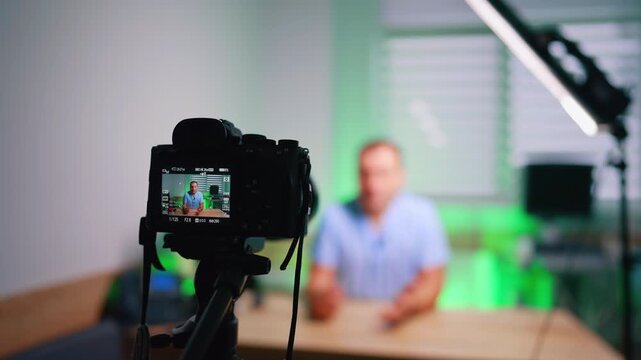 Man sitting at desk on the camera display. Doctor talks for video giving advice for patients in blog.