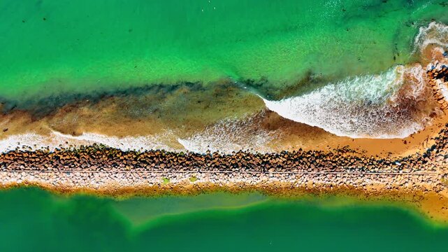 Stone dam with waves rolling to. Sea-green waterscape of the Pacific Ocean in Santa Barbara, California, USA. Top view.