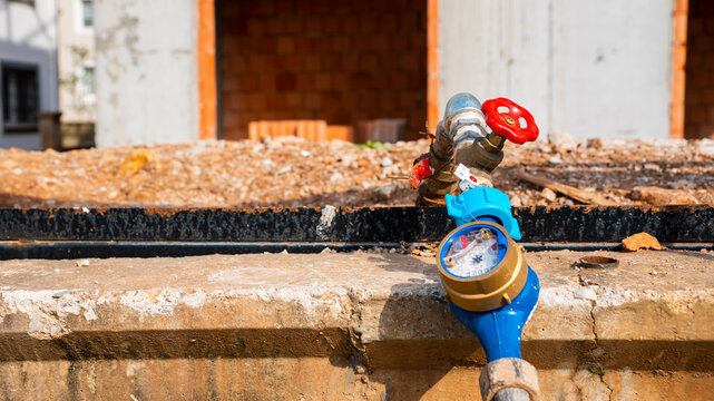 Close-up of a domestic water meter gauge with valve handle on a residential construction site