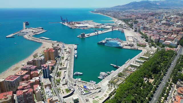 Malaga, Spain - July 17, 2025 High angle flyover of Malaga harbor and the historic Gibralfaro medieval fortress on the hilltop. Scenic coastal cityscape with luxury boats and Mediterranean sea in Anda