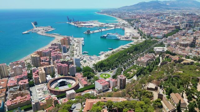 Malaga, Spain - July 17, 2025 High angle flyover of Malaga harbor and the historic Gibralfaro medieval fortress on the hilltop. Scenic coastal cityscape with luxury boats and Mediterranean sea in Anda