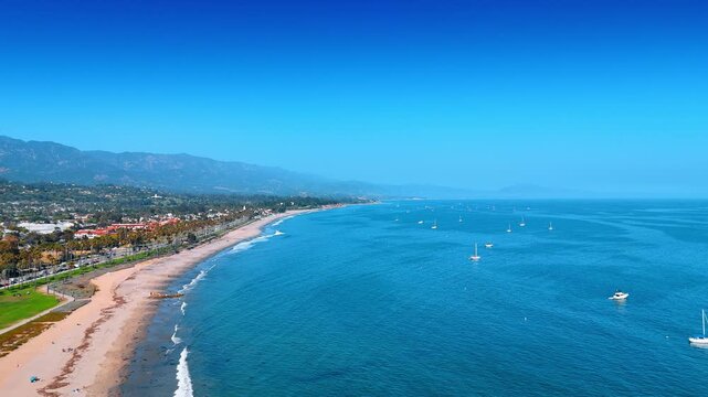 Stunning blue waterscape with boats and yachts on. Drone flight along the beach in Santa Barbara, California, USA.