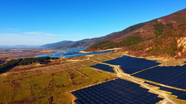 Flight over the sunny fields covered with solar panels. Modern technology for sustainable energy production.