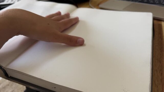 Slow motion opening sketchbook with hand on blank page