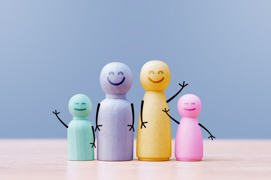 Colorful wooden family figures with smiling faces on blue background. Parenthood, childcare, family support and community concept for psychology, education, social care or insurance marketing.