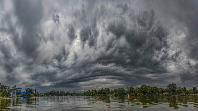 Dark shelf cloud above lake with dramatic storm atmosphere
Massive layered storm cloud reflected above calm water creating intense weather landscape scenery.