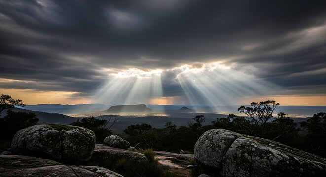 Dramatic Sun Rays Breaking through Clouds over Rocky Landscape