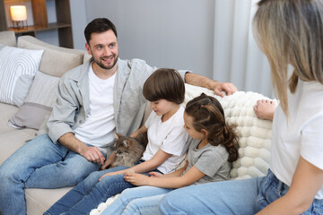 Obraz premium Family with their cute cat on sofa at home. Adorable pet