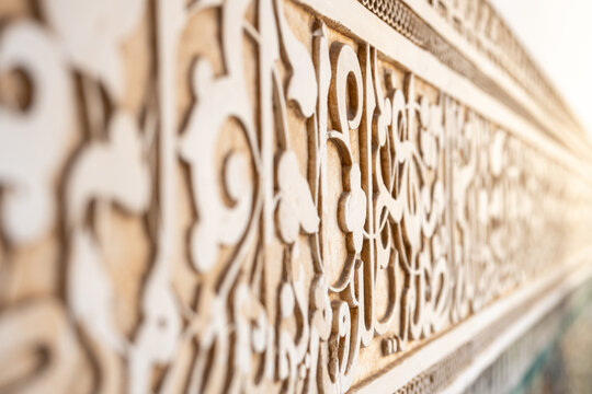 Ornamental sculpted plaster is seen at Madrasa Ben Youssef in Marrakech, Morocco. The design shows intricate patterns that reflect the cultural heritage of the region.