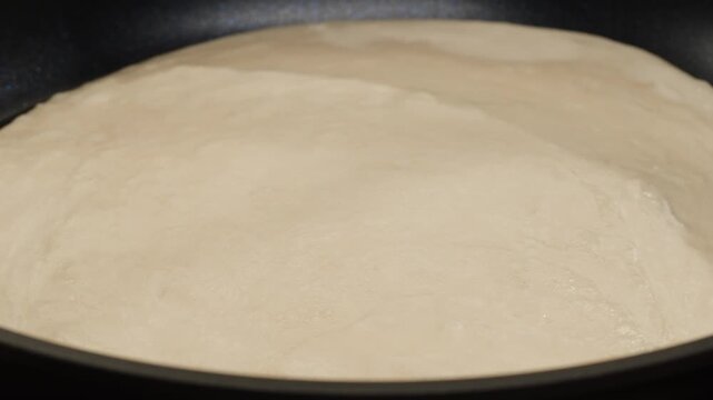 Indian food cooking, Close-up view of a woman's hand flipping a naan roti or bread on hot metal pan. Naan or bread cooking process.