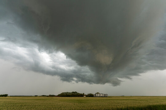 Dramatic shelf cloud looms over a rural landscape with grain silos