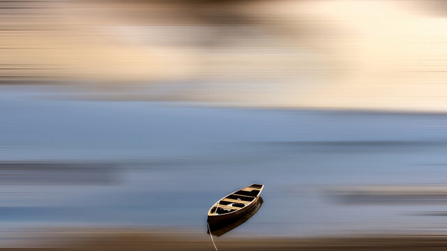 Solitary canoe drifts on water with motion blur effect