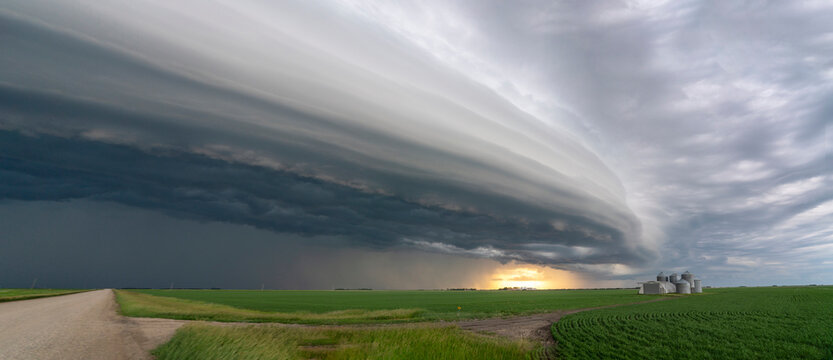 Dramatic shelf cloud formation over a rural landscape with grain silos