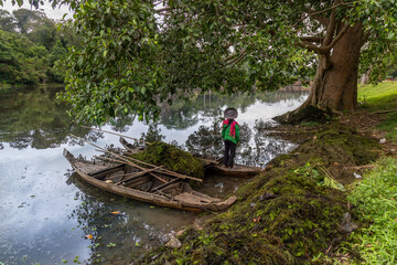 Fototapeta premium Women in boats in Ankor Wat clean up aquatic plants from a lake surrounded by lush jungle vegetation. Siem Rep, Cambodia