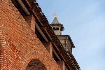 Brick Fortress Tower Under Pale Sky, Red Brick Wall With Round Arches, Wooden Spire Crowned With Gilded Cross, Weathered Masonry Textures, © Egor Lint