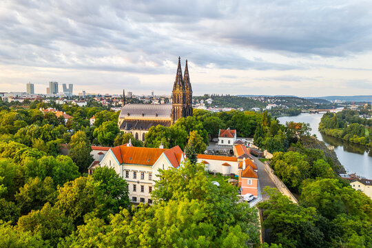 Morning light bathes Vysehrad Basilica of St. Peter and St. Paul in golden hues. Surrounded by lush greenery, the historic church stands tall as the city begins to awaken.