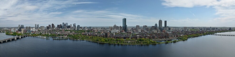 Obraz premium Panoramic aerial drone view of Boston Back Bay skyline, Prudential Tower, and Charles River Esplanade on a clear summer day, featuring historic brownstones and city skyscrapers, USA.