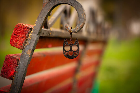 Black cat charm pendant hanging on rustic park bench