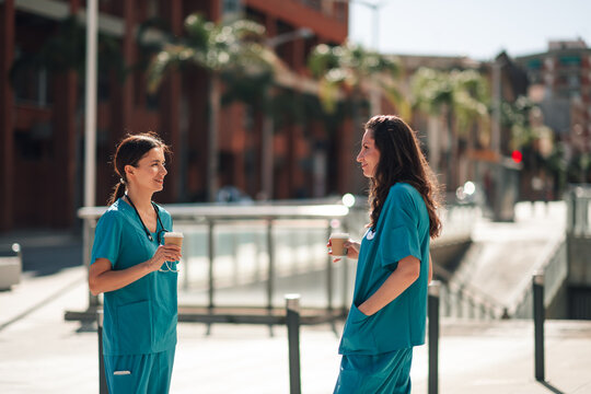 Healthcare professionals having coffee break outside, discussing work and sharing experiences in urban setting