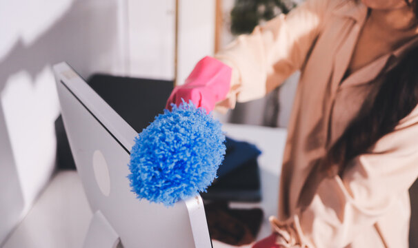Person cleaning the room, cleaning staff is using cloth and spraying disinfectant to wipe the tables in the company office room. Cleaning staff. Maintaining cleanliness in the organization.