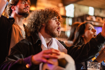 Fototapeta premium Furious sports fan shouting at a television screen in frustration over a lost match.