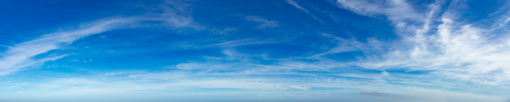 Cielo azul brillante y despejado con finas nubes cirros. Panorama minimalista con brillantes tonos azules y delicadas estelas de nubes cirros que atraviesan la imagen.