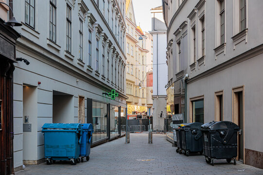 Empty European Alley With Trash Bins and Pharmacy Green Cross Sign on Narrow City Street