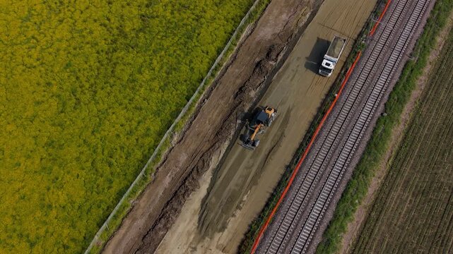 Heavy machinery performs precise earthmoving and grading to prepare the foundation for future high-speed train tracks on this northern Italian site.