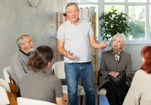 Engaged senior man standing and sharing his opinion during an interactive group meeting