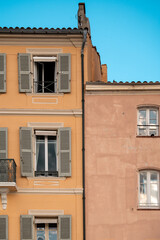 Obraz premium Colorful building facades with green shutters and multiple windows under a clear blue sky in Saint Tropez, France.