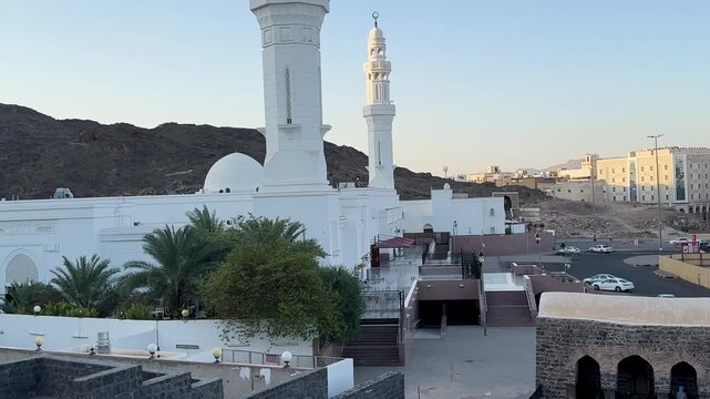 A sweeping panoramic view of the modern Al Fath Mosque, the historic stone structures, and Mount Sila in Medina, Saudi Arabia.